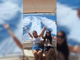 Two friends enjoy a joyful moment on a boat, celebrating their day on the water with smiles and raised hands, perfect for capturing the essence of fun outings.