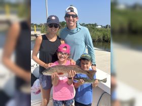 A joyful family proudly displays their fishing catch, showcasing a successful day on the water. Perfect for family fishing trips and outdoor adventures.
