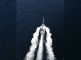 Aerial view of a speedboat cruising through deep blue waters, showcasing its sleek design and powerful wake — perfect for thrilling adventures on the open sea.