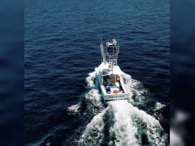 A fishing boat navigates through deep blue waters, showcasing an active day on the sea with guests enjoying the ride.