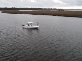 A fishing boat is seen on calm waters, with two individuals enjoying a day out on the water — perfect for outdoor adventures and fishing trips.