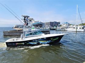 A sleek fishing boat, the 'Gunstar,' navigates through the waters, showcasing its vibrant design and fishing gear — perfect for deep-sea adventures.