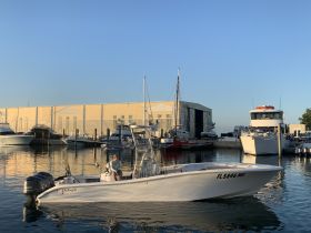 A sleek speedboat named 'Yellowfin' docked at the marina, showcasing its modern design and tranquil surroundings.