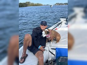 A man enjoys a relaxing moment on a boat with his dog, showcasing the joy of companionship on the water.