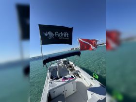 A well-equipped boat interior showcasing the helm and seating area, perfect for adventure outings. The visible flags indicate the boat's affiliation with Adrift Adventures.