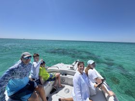 A joyful family enjoys a sunny day on the water, capturing memories aboard their boat with the beautiful ocean as a backdrop.