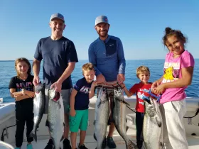 A joyful family celebrates their successful fishing trip, proudly displaying their catch on a boat — a perfect memory of fun and adventure on the water.