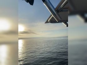 An unclear view of the ocean with a portion of a boat visible, lacking identifiable features or subjects.