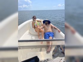 A couple enjoys a sunny day on the boat, relaxing with drinks in hand — the perfect setting for a fun day on the water.