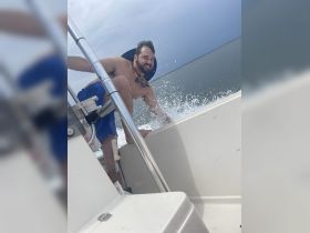 A man enjoys the thrill of the boat ride, splashing water and smiling, capturing the essence of fun on the water.