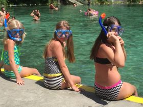 Three children prepare for a snorkeling adventure in crystal-clear waters, showcasing the excitement of underwater exploration and family fun.