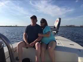A couple enjoys a serene moment together on a boat, surrounded by tranquil waters and a beautiful sky — perfect for romantic outings or special occasions.
