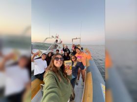 A lively group of friends celebrates on a boat, joyfully holding up their favorite Haribo snacks — perfect for fun outings and memorable moments on the water.