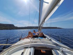 A group of friends relaxes on the deck of a sailboat, enjoying the sun and beautiful views while sailing — a perfect day on the water.