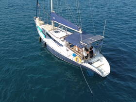 Aerial view of a sailboat navigating through clear waters, showcasing its sleek design and onboard features.