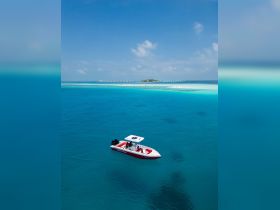 A stunning aerial view of a speedboat cruising through crystal-clear turquoise waters, showcasing the beauty of a tropical paradise.