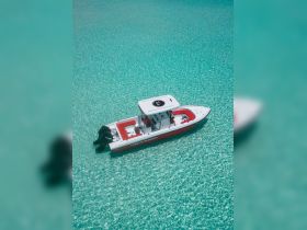 A stunning aerial view of a speedboat cruising through crystal-clear turquoise waters, showcasing its sleek design and vibrant colors.