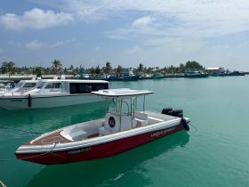 A sleek speedboat named 'Unique Shadow' docked in clear turquoise waters, surrounded by other vessels in a vibrant marina setting.