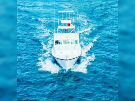 A stunning aerial view of a yacht cruising through vibrant blue waters, showcasing its sleek design and elegance on the open sea.