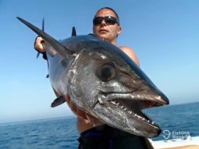 A fisherman proudly displays a large fish caught at sea, showcasing the thrill of deep-sea fishing adventures.