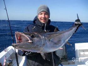 A proud angler holds up a large catch while fishing in the open ocean, showcasing the thrill of deep-sea fishing adventures.