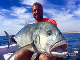A fisherman proudly displays a large catch on a boat, showcasing the thrill of deep-sea fishing adventures.