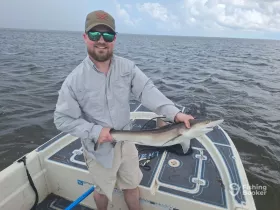 A proud angler holds up a freshly caught shark while fishing from a boat, showcasing the thrill of deep-sea fishing adventures.