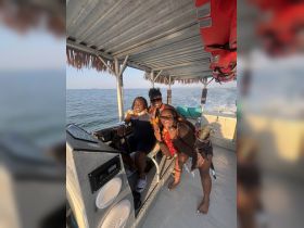 A lively group of friends enjoys a fun moment aboard a boat, showcasing their excitement and celebration on the water.