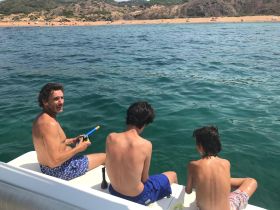 A family enjoys a day of snorkeling off the boat, with a beautiful beach in the background — perfect for summer adventures on the water.