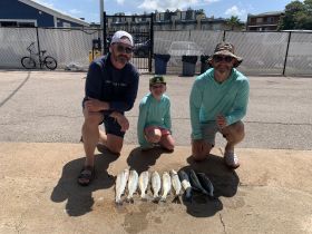 A group of anglers proudly displays their catch of the day, showcasing a successful fishing trip with family — a perfect memory of time spent on the water.