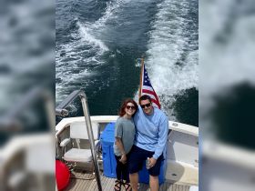 A happy couple poses on the deck of a boat, enjoying their time on the water — perfect for romantic getaways or fun outings.