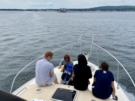 A group of family members enjoys a relaxing moment on the bow of a boat, surrounded by scenic waters — perfect for family outings and adventures.
