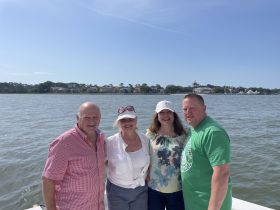 A cheerful group of friends poses for a photo on a boat, enjoying a sunny day on the water — perfect for family outings or group celebrations.