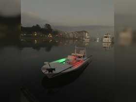 A serene evening view of a boat docked in calm waters, illuminated by green and red lights, creating a picturesque scene perfect for nighttime boating adventures.