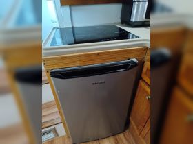 A close-up view of a kitchen area on a boat featuring a Whirlpool refrigerator and an induction cooktop, showcasing essential amenities for onboard cooking and storage.