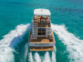 Aerial view of the 'Searinus' yacht cruising through crystal-clear waters, showcasing its sleek design and spacious deck — perfect for luxury outings in the Bahamas.