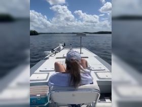 A person relaxes on the deck of a boat, enjoying the serene water and beautiful sky — a perfect moment for unwinding on the water.