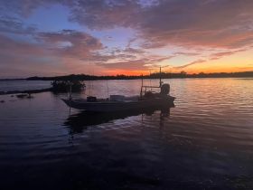 A serene sunset view of a fishing boat anchored in calm waters, perfect for evening excursions and fishing trips.