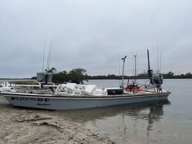 A fishing boat is docked on the shore, showcasing its structure and equipment, ideal for anglers looking for a day on the water.