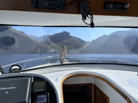 A woman enjoys the stunning mountain scenery while relaxing on the bow of a boat, capturing the essence of a perfect day on the water.