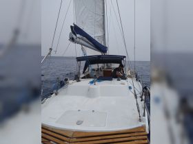 A view of the interior of a sailboat featuring the helm and seating area, with a person engaged in activity, showcasing the cozy space for navigation and relaxation.