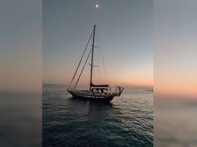 A serene view of a sailboat docked at sunset, showcasing the tranquil beauty of the evening sky and calm waters.