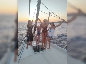 A joyful group of friends celebrates on the deck of a yacht at sunset, capturing the essence of fun and camaraderie on the water.