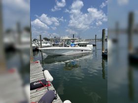 Two individuals prepare for a fishing trip aboard their boat, 'Sweet Your Fish,' at the dock, showcasing a perfect day for water adventures.