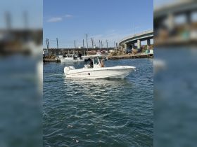 A sleek speedboat navigates through the water, showcasing its design and performance while cruising in a scenic harbor.