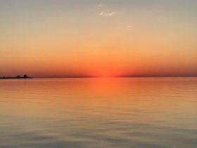A stunning sunset casts vibrant colors over calm waters, creating a picturesque scene ideal for romantic evenings or peaceful reflections by the shore.