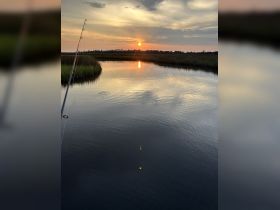 A serene sunset view over calm waters, perfect for fishing enthusiasts enjoying the tranquility of nature.