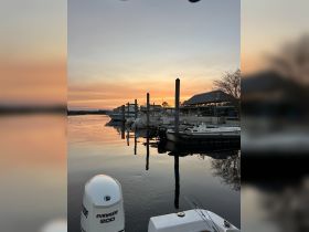 A serene sunset view over a dock filled with boats, reflecting beautifully on the calm water — a perfect setting for evening boat outings.