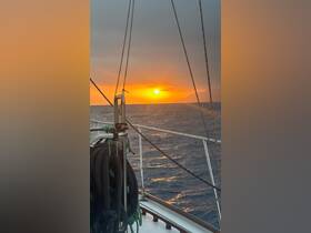 A stunning sunset view from the deck of a sailboat, showcasing the tranquil ocean and distant land — perfect for romantic evening cruises.