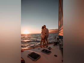 A couple shares a romantic moment on the deck of a sailboat at sunset, creating the perfect backdrop for unforgettable sailing experiences.